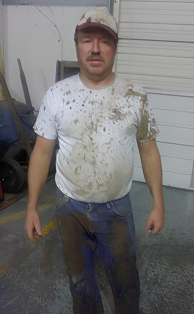 Man wearing dirty clothes in a garage.